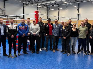 Die Teilnehmer des Lehrgangs auf einem Gruppenbild vor einem Boxring in der Trainingshalle.