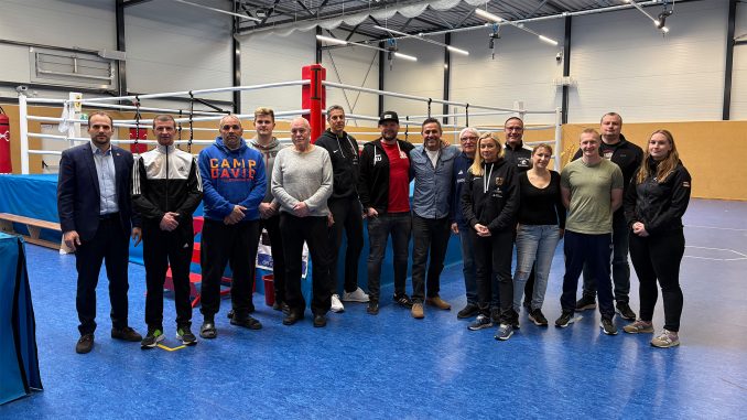 Die Teilnehmer des Lehrgangs auf einem Gruppenbild vor einem Boxring in der Trainingshalle.