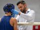 Ein Ringarzt untersucht in einer Unterbrechung dews Kampfes einen verletzten Boxer an den Ringseilen